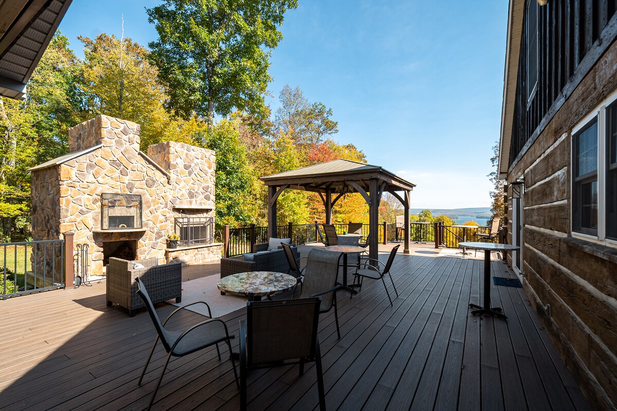 Large deck with stone fireplace, gazebo, and distant lake view